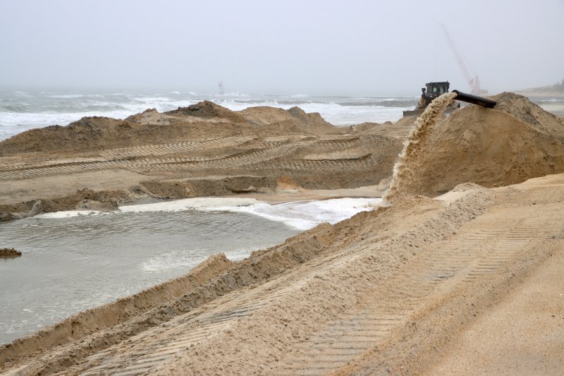 Slurry pours from a pipe on the north side of the inlet, creating a manmade river in the sand. The buildup of sand helps counteract beach erosion and protects Coastal Highway and the Charles W. Cullen Bridge.